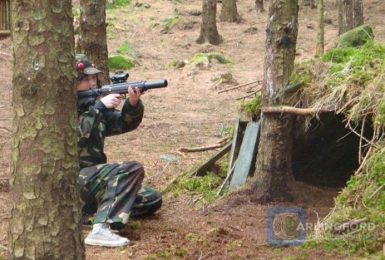 Person in camouflage aiming a laser gun in the forest