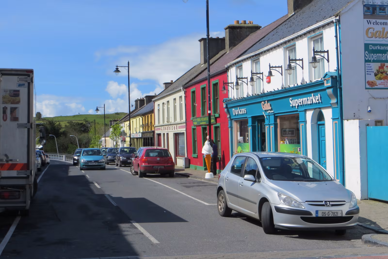 The main street of Louisburgh village in County Mayo, with small shops and houses lining the road