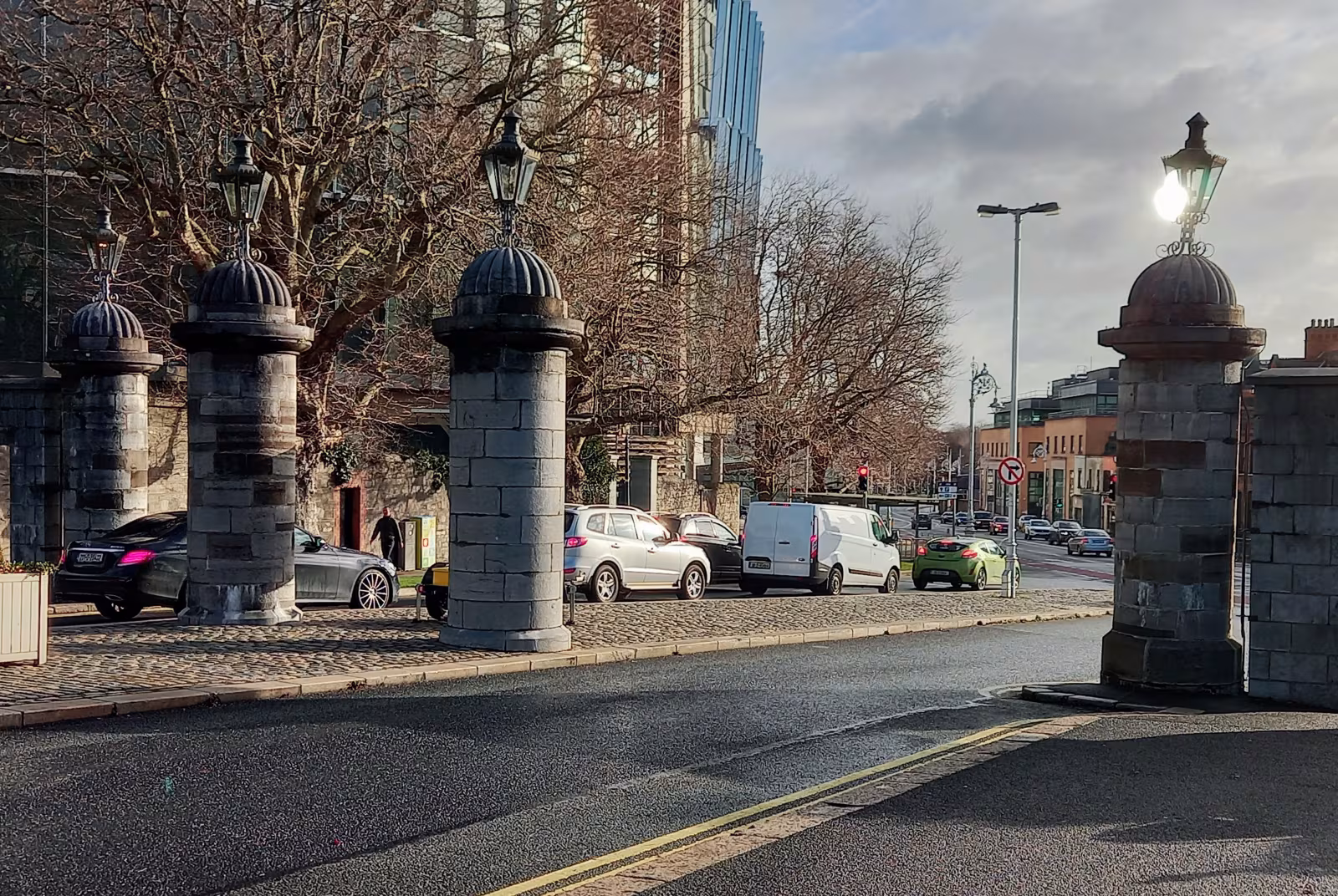 The ornate Parkgate Street entrance gates to Phoenix Park in Dublin, with iron railings, stone pillars and a view of the main road into the park