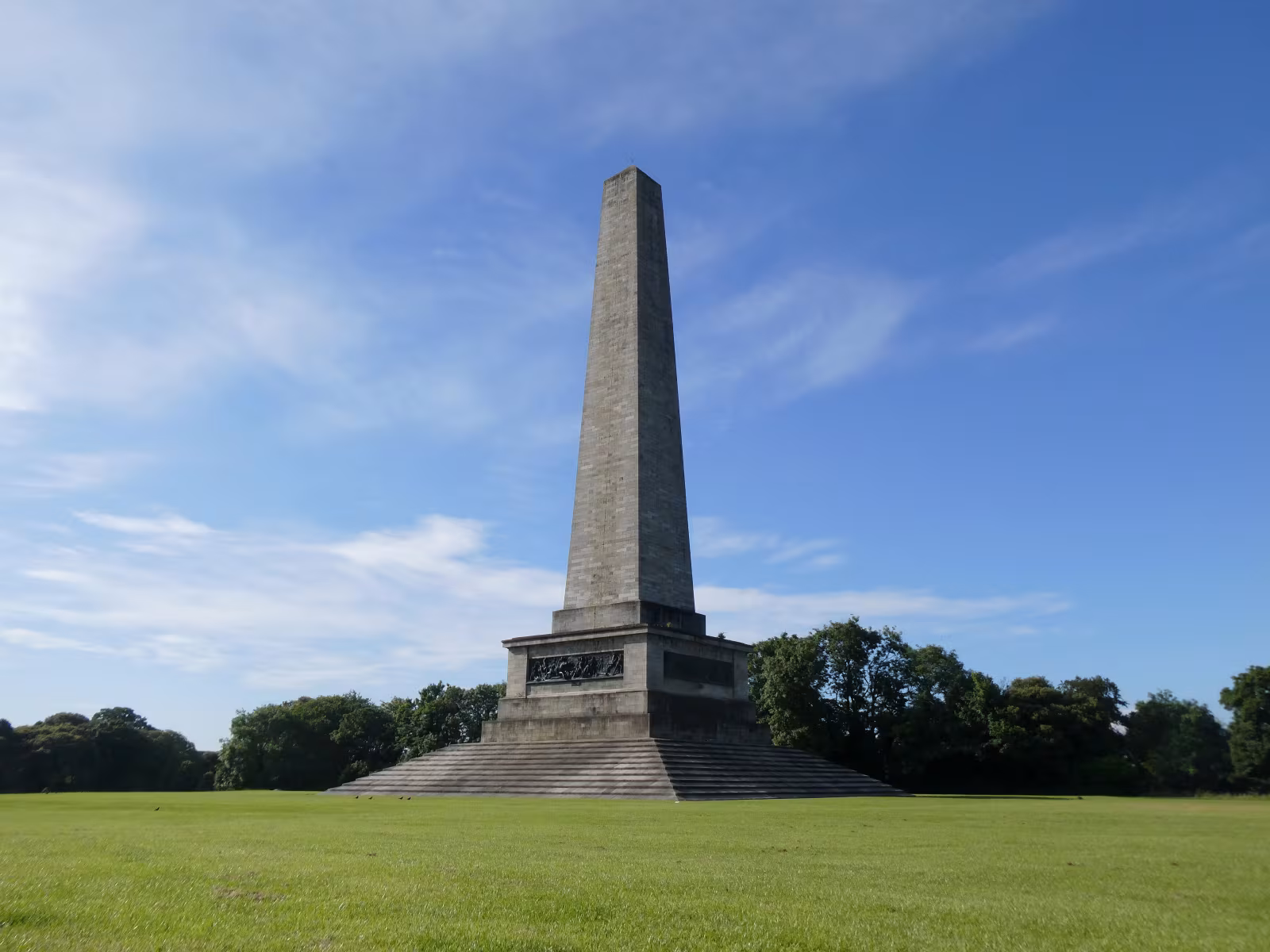The Wellington Monument obelisk in Phoenix Park Dublin, a tall stone column rising from green parkland with a clear sky behind it